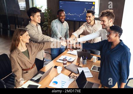 Concept de soutien et de travail d'équipe. Un groupe de jeunes gens d'affaires multiculturels qui se font frapper le poing au-dessus du bureau Banque D'Images