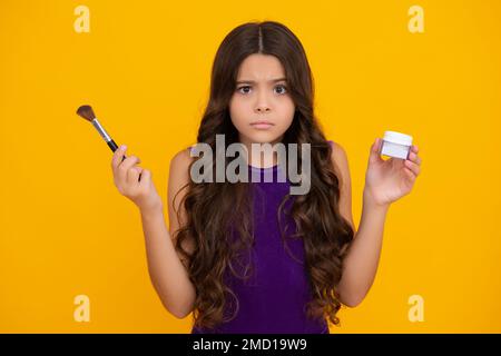 Produits de maquillage pour enfants. Maquillage adolescent artiste appliquez la poudre pour le visage avec une brosse à maquillage. Beauté, et cosmétiques pour les adolescents. Adolescente en colère, bouleversée Banque D'Images