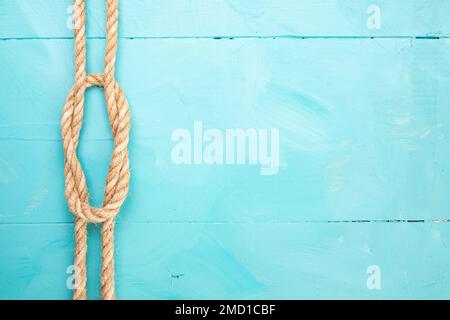 Corde de jute avec un nœud sur les planches peintes en bleu, toile de fond marine, mise au point douce gros plan Banque D'Images