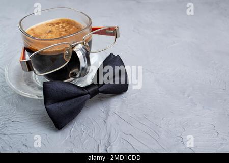 Tasse de café transparente avec lunettes et noeud papillon noir Banque D'Images