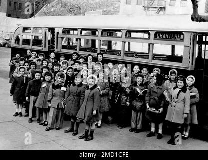 Une photographie vintage d'un grand groupe de garçons et de filles à New York debout devant leur autobus scolaire, vers 1952. Banque D'Images