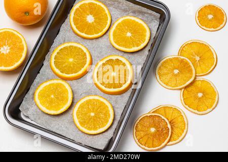 Sécher les tranches d'orange sur la table. Tranches d'orange fraîches sur la plaque de cuisson Pose à plat. Arrière-plan blanc. Banque D'Images