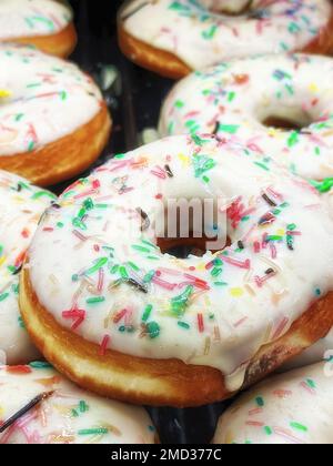 Beignets blancs à glaçage frais et au chocolat sur le marché. Pâtisseries et produits sucrés. Modèle vertical Banque D'Images