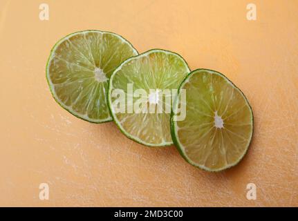 Tranches de fruits à la chaux persane sur une planche à découper orange. La chaux est un agrumes. Cette chaux est une croix entre la chaux-clé et le citron Banque D'Images