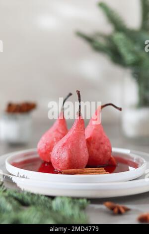 Assiette de poires pochées sucrées au vin rouge sur fond clair. Banque D'Images