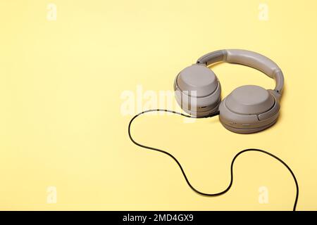 Casque supra-aural sans fil gris clair avec possibilité de connexion filaire sur un arrière-plan couleur sable. Écouteurs pour jouer ou écouter Banque D'Images