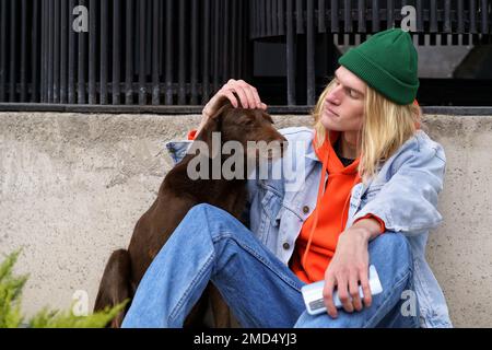 Hipster gars assis dans la rue avec le chien errant bouleversé, problème des animaux sans abri Banque D'Images