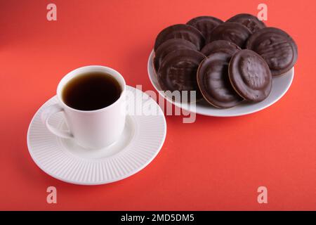 phototasse de café et biscuits enrobés de chocolat dans une assiette sur fond coloré Banque D'Images