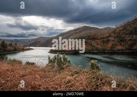 Une vue sur un beau lac entouré de montagnes couvertes de fougères rouges. Banque D'Images