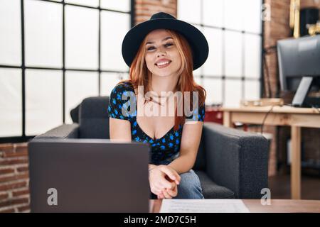 Jeune femme caucasienne musicienne souriant confiante en utilisant un ordinateur portable dans un studio de musique Banque D'Images