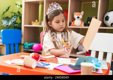 Adorable fille blonde étudiante portant le papier de coupe de la couronne de princesse à la maternelle Banque D'Images