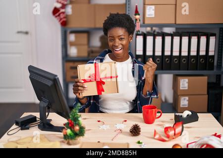 Une femme afro-américaine debout par mannequin dans une petite entreprise à noël criant fière, célébrant la victoire et le succès très excitée avec AR élevé Banque D'Images