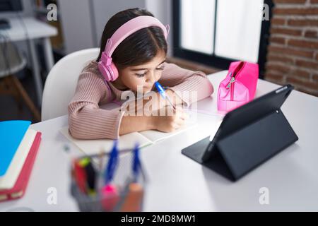 Adorable jeune fille hispanique étudiante assise sur une table étudiant en classe Banque D'Images