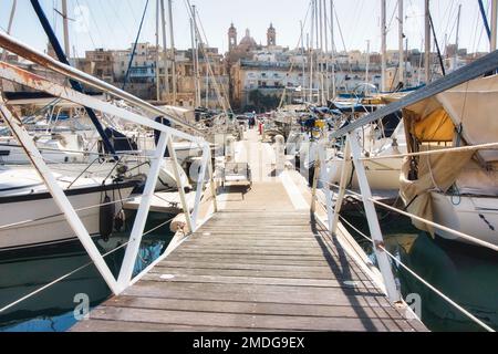 Point de vue tiré de l'entrée d'une jetée en bois menant à des yachts coûteux dans une marina Banque D'Images