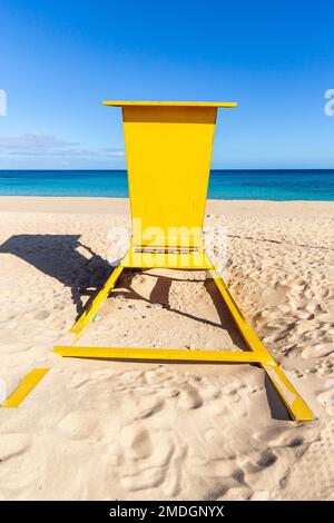 cabine de sauveteur jaune vif, se tenant face à un horizon bleu intense. Banque D'Images