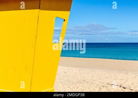 cabine de sauveteur jaune vif, se tenant face à un horizon bleu intense. Banque D'Images