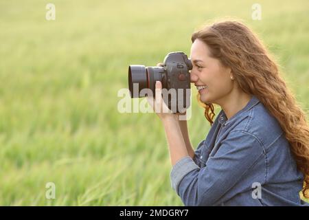 Portrait en vue latérale d'une femme prenant des photos dans un champ Banque D'Images