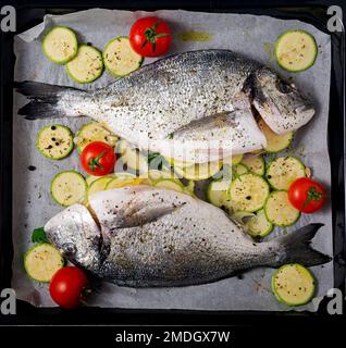 Poisson dorado cru avec des ingrédients pour faire sur une plaque de cuisson. Vue de dessus Banque D'Images