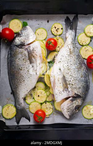 Poisson dorado cru avec des ingrédients pour faire sur une plaque de cuisson. Vue de dessus Banque D'Images