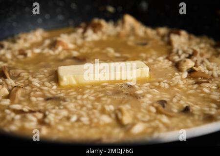 Processus de cuisson du risotto. Arborio riz et morceau de beurre dans poêle à frire dans la cuisine maison. Plat de cuisine italienne Banque D'Images