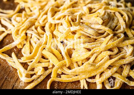 Pâtes faites maison. Pâtes italiennes fraîches et crues sur une table de cuisine en bois. Photo de haute qualité Banque D'Images