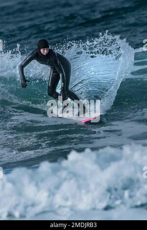 Un surfeur qui profite de l'hiver en surfant à Fistral à Newquay, en Cornouailles, au Royaume-Uni. Banque D'Images