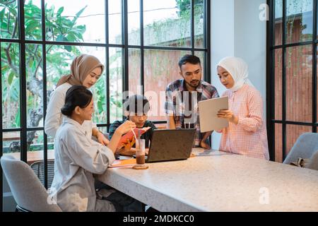 Cinq étudiants asiatiques sont occupés à travailler ensemble sur des missions Banque D'Images