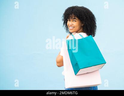 Dos, portrait et femme noire avec des sacs, shopping et acheter des articles coûteux avec fille sur fond bleu studio. Mockup, femme jamaïcaine et Banque D'Images