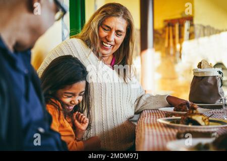 Heureux grands-parents latins ayant plaisir à manger avec la petite-fille à la maison de patio - Focus sur le visage de grand-mère Banque D'Images