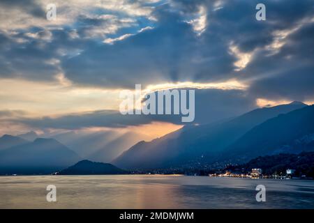 tard dans la soirée en été au lac de côme avec des montagnes brumeuses et des rayons de soleil qui brillent à travers les nuages Banque D'Images