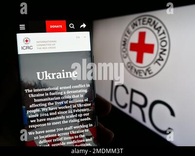 Personne tenant un smartphone avec le site Web du Comité international de la Croix-Rouge (CICR) à l'écran avec logo. Concentrez-vous sur le centre de l'écran du téléphone. Banque D'Images