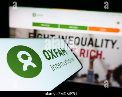 Téléphone portable avec logo de la confédération Oxfam International à l'écran devant le site. Mise au point au centre-gauche de l'écran du téléphone. Banque D'Images