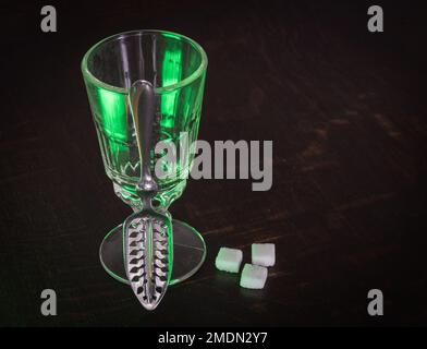 Verre Absinthe traditionnel et cuillère avec cubes de sucre sur table en bois Banque D'Images