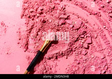 Ombres à paupières roses écrasées avec pinceau ou outil de mélange d'applicateur sur fond rose Banque D'Images