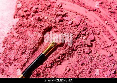 Ombres à paupières roses écrasées avec pinceau ou outil de mélange d'applicateur sur fond rose Banque D'Images