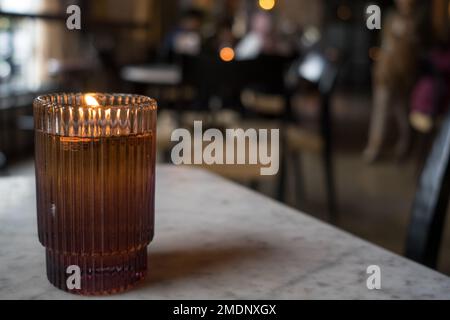 Bougie allumée dans un pot en verre brun sur la table en marbre. Banque D'Images