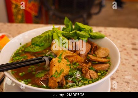 Pho Bo ou soupe vietnamienne avec boulettes de viande et de bœuf servies dans un bol blanc. Banque D'Images