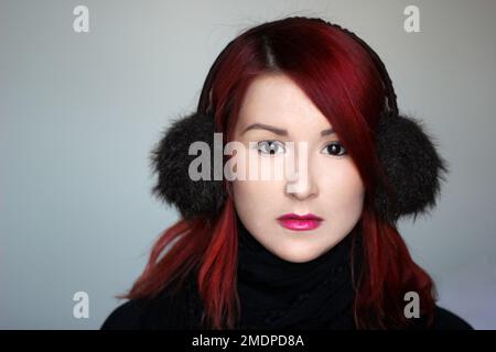 REDHEAD fille dans les couvre-oreilles en fourrure et foulard noir Banque D'Images