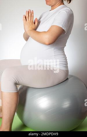 Une fille enceinte avec un gros ventre fait du yoga sur un tapis. Sports et grossesse. Santé des femmes. Banque D'Images