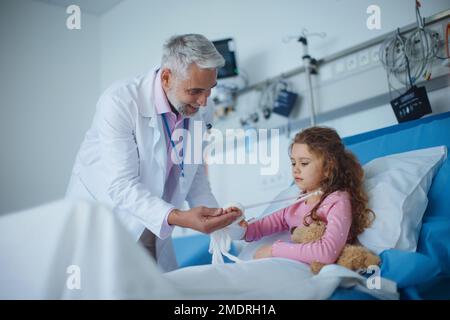 Médecin examinant la petite fille avec le bras cassé. Banque D'Images