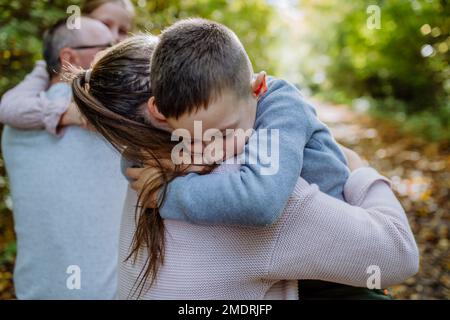 Petit garçon embrassant sa mère pendant la promenade en famille dans la forêt. Banque D'Images