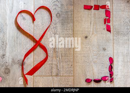 Carte de Saint-Valentin avec coeur en ruban rouge et espace vierge. L'arrière-plan de la carte est en bois Banque D'Images
