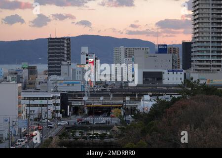 Akashi, Japon - 29 décembre 2022: Coucher de soleil sur la circulation à l'intersection sous les voies de train élevées dans la petite ville Banque D'Images