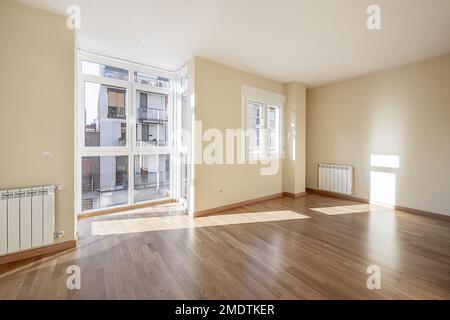 Chambre vide avec parquet en chêne clair dans une maison avec une baie vitrée en aluminium blanc et des fenêtres assorties Banque D'Images