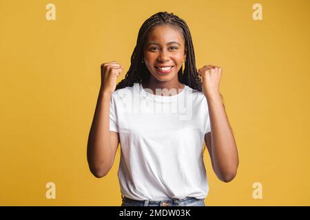 Une femme moderne emballée et excitée qui célèbre la réalisation de ses objectifs, en élevant des poings isolés sur une dame jaune aux cheveux sombres, se réjouit, criant oui dans l'euphorie, la victoire et la victoire Banque D'Images