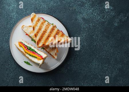 Trois sandwichs maison avec saucisse, fromage et arugula sur fond de béton sombre Banque D'Images