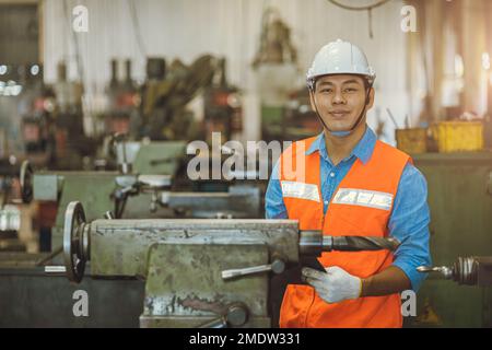 Portrait asiatique ingénieur adulte homme travailleur dans l'atelier de machines avec liste de contrôle sourire heureux dans sécurité hardhat Banque D'Images