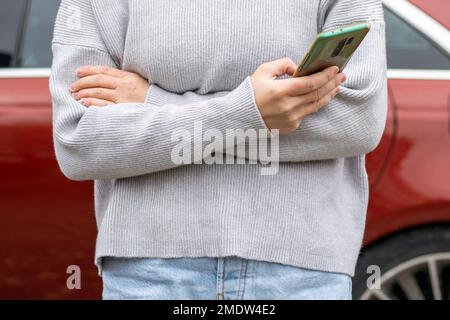 femme devant la porte latérale rouge voiture dans chaud pull-over bleu jeans Banque D'Images