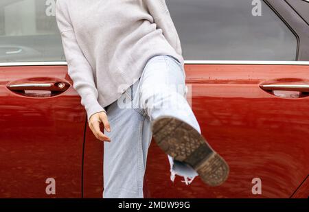 femme devant la porte latérale rouge voiture dans chaud pull-over bleu jeans Banque D'Images