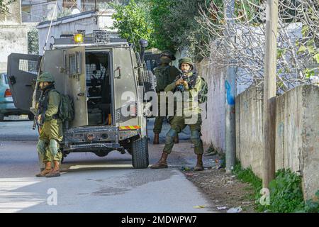 Naplouse, Palestine. 23rd janvier 2023. Les soldats israéliens se tiennent sur la garde tandis que d'autres soldats entourent et cherchent une maison, pendant le raid dans le village de Salem, à l'est de Naplouse, en Cisjordanie occupée. Les forces de l'armée israélienne se sont rompues dans le village de Salem et ont fouillé plusieurs maisons appartenant aux Palestiniens. Crédit : SOPA Images Limited/Alamy Live News Banque D'Images